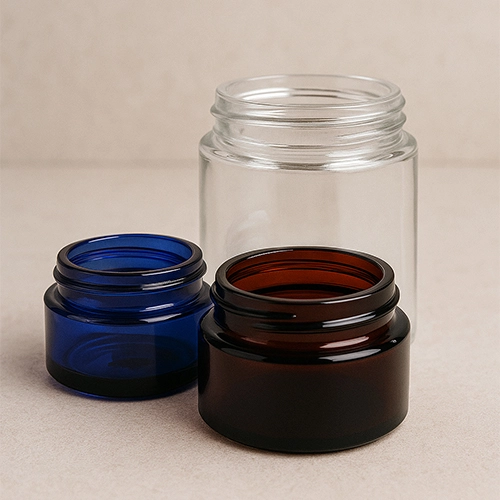 Redex Glass cosmetic cream jars in clear, amber, and cobalt blue glass, displayed on a neutral background.
